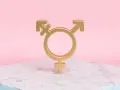 Złoty symbol trans, łączący symbole Wenus, Marsa i hermafrodyty, na marmurowej podstawie.