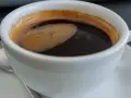 Aromatic coffee in a white cup, a moment to ponder: czy kawa jest zdrowa? The rich crema hints at a complex flavor.