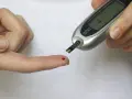 Kropla krwi na palcu czeka na glukometr. Kontrola poziomu cukru na czczo, ważna dla osób z cukrzycą.