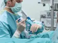 Lekarz w masce i rękawiczkach trzyma urządzenie do biopsji prostaty.