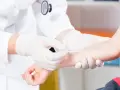 Lekarz w białej rękawiczce wykonuje test skórny na ramieniu pacjenta.