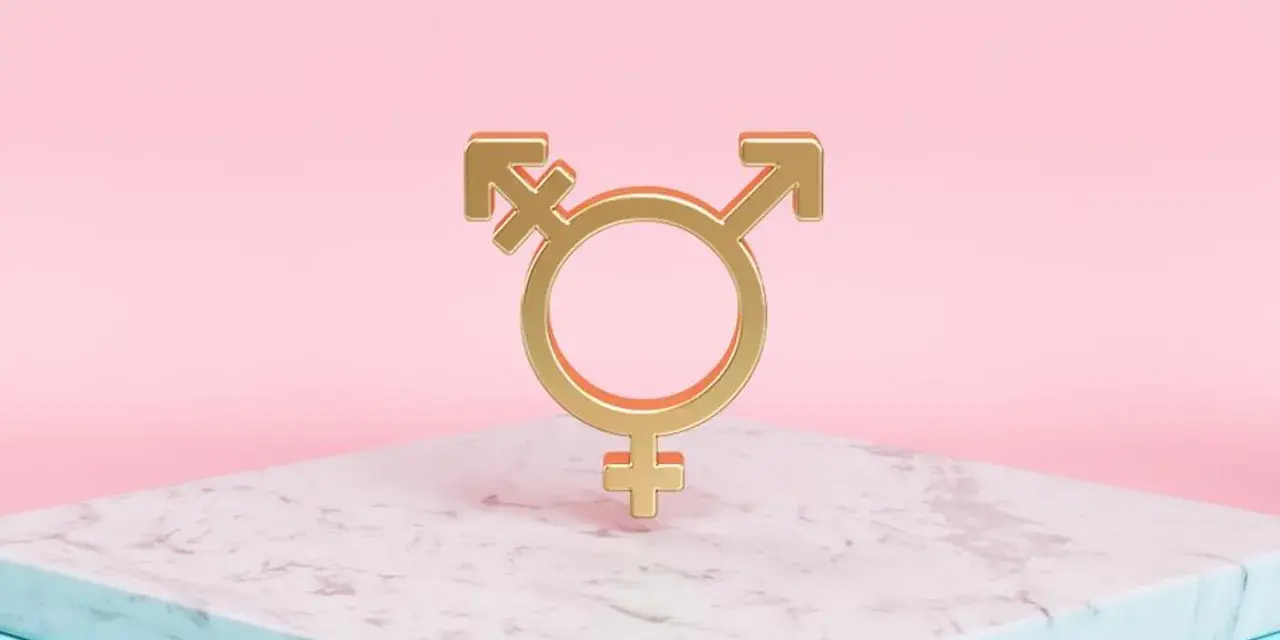 Złoty symbol trans, łączący symbole Wenus, Marsa i hermafrodyty, na marmurowej podstawie.