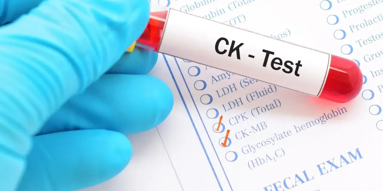Ręka w niebieskiej rękawiczce trzyma probówkę z krwią do testu CK, czyli kinazy kreatynowej. Zaznaczono opcje CPK (Total) i CK-MB.