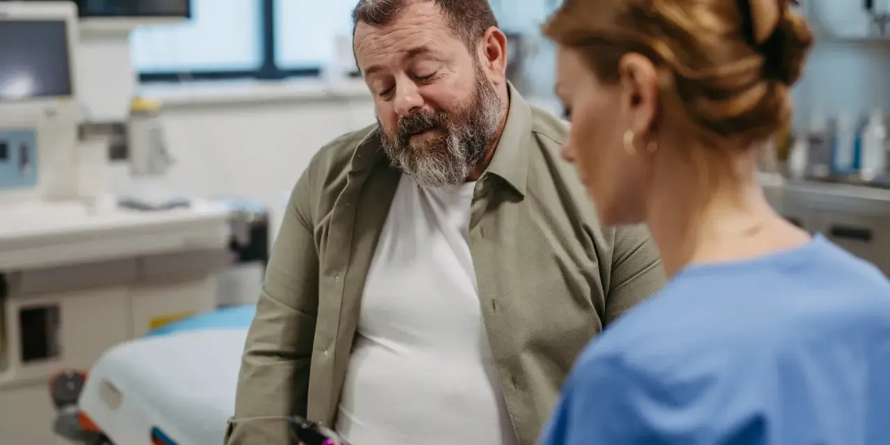 Lekarz pokazuje pacjentowi glukometr w gabinecie lekarskim.