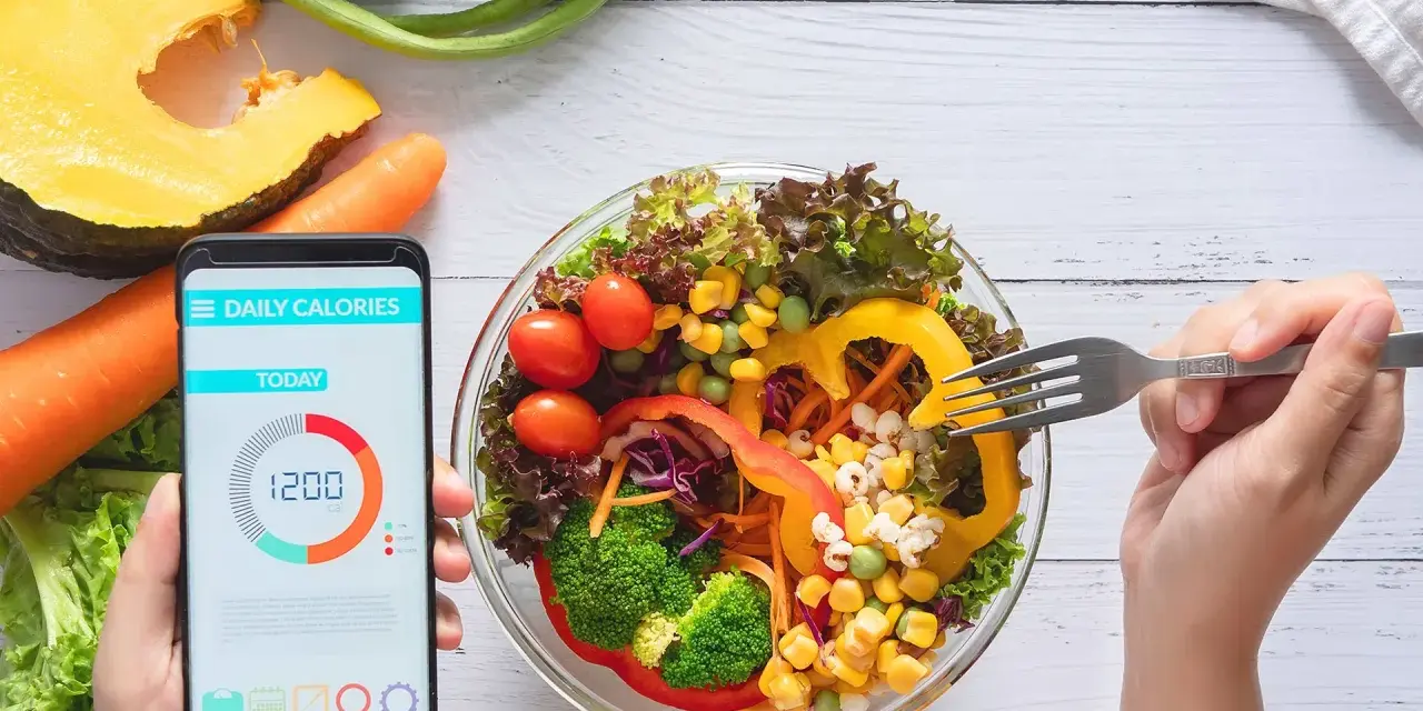 Zdrowa sałatka i aplikacja do liczenia kalorii na telefonie. Dziś spożyto 1200 kcal.