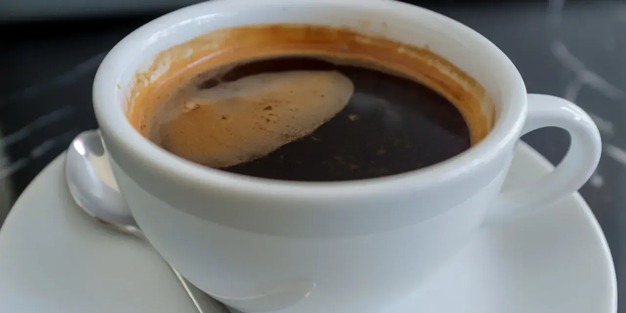 Aromatic coffee in a white cup, a moment to ponder: czy kawa jest zdrowa? The rich crema hints at a complex flavor.