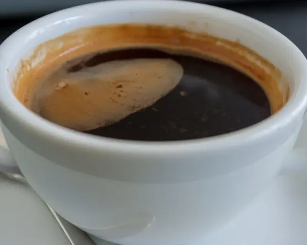 Aromatic coffee in a white cup, a moment to ponder: czy kawa jest zdrowa? The rich crema hints at a complex flavor.