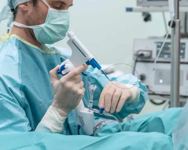 Lekarz w masce i rękawiczkach trzyma urządzenie do biopsji prostaty.