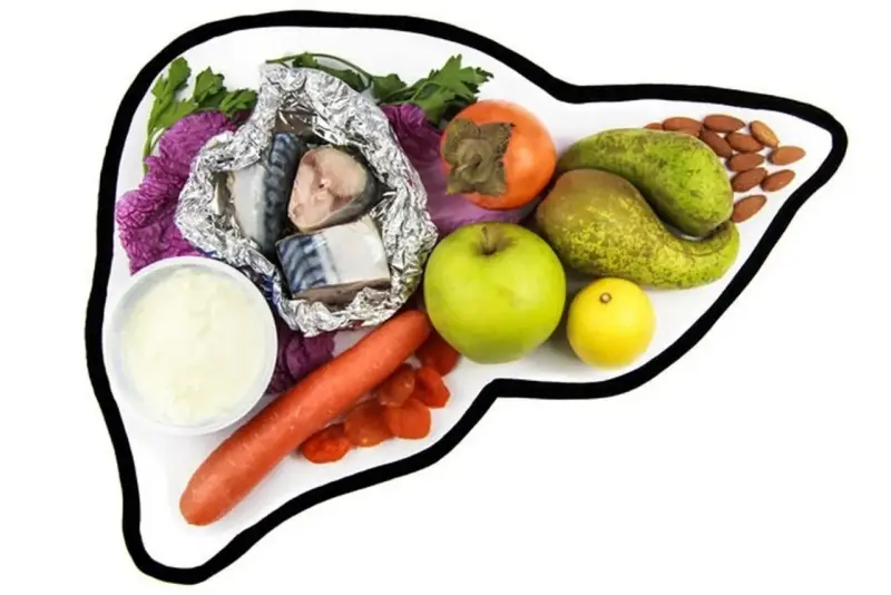 Zdrowe produkty na talerzu w kształcie wątroby: ryby, owoce, warzywa i orzechy. Idealne składniki na dietę wątrobową.